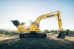a yellow excavator sitting on top of a dirt field